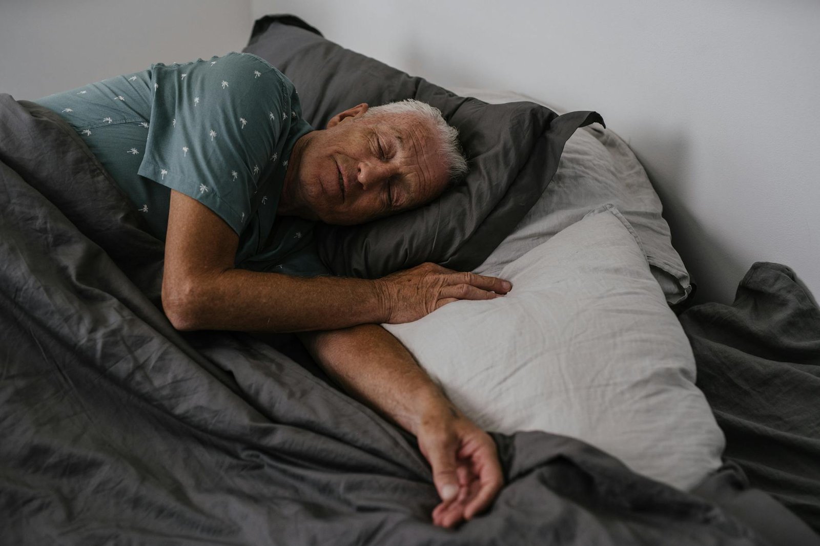 an elderly man sleeping on the bed