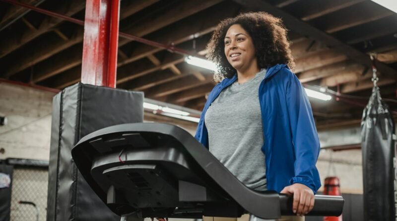 Smiling black woman standing on treadmill