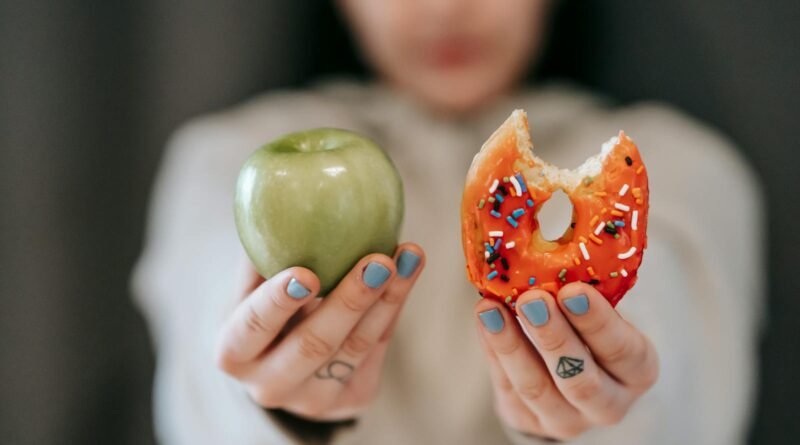 Woman showing apple and bitten doughnut