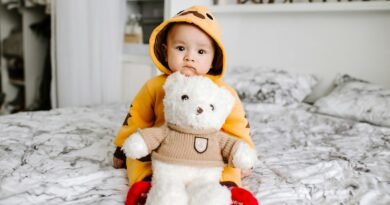 toddler sitting on bed beside white bear plush toy