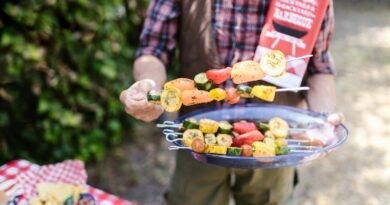 Person Holding a Platter of Sliced Fruits and Vegetables on Skewers