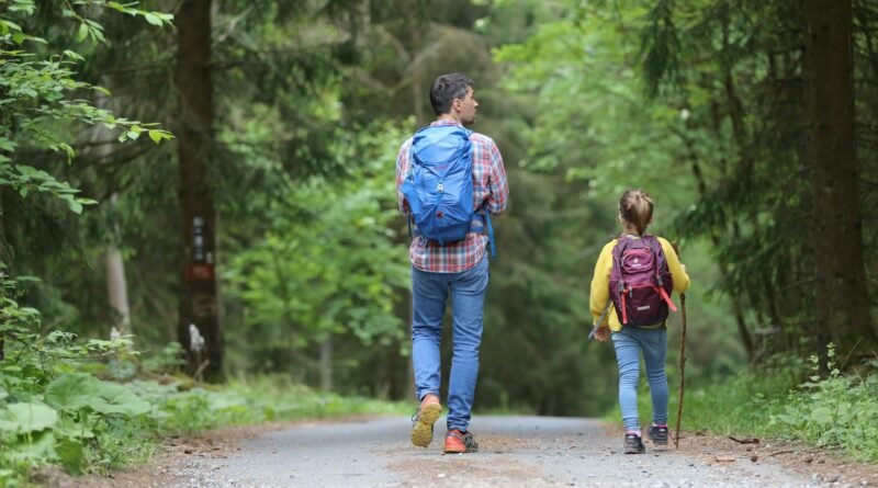 man in blue jacket and blue denim jeans walking on dirt road during daytime