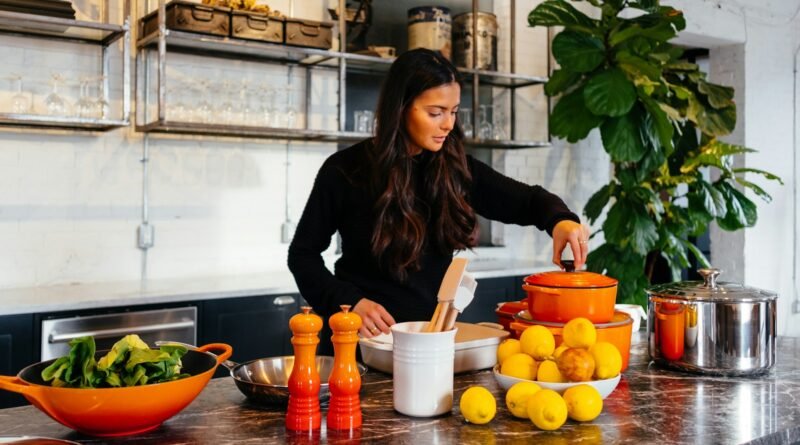 woman standing in front of fruits holding pot's lid