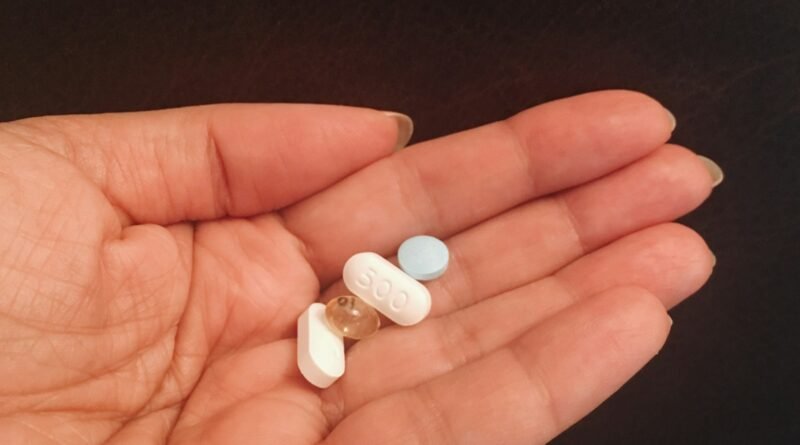 person holding four assorted medicine tablets