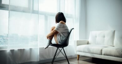 woman sitting on black chair in front of glass-panel window with white curtains