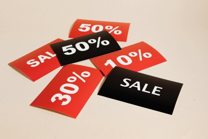 Red and black sale tags showing various discount percentages on a beige background.